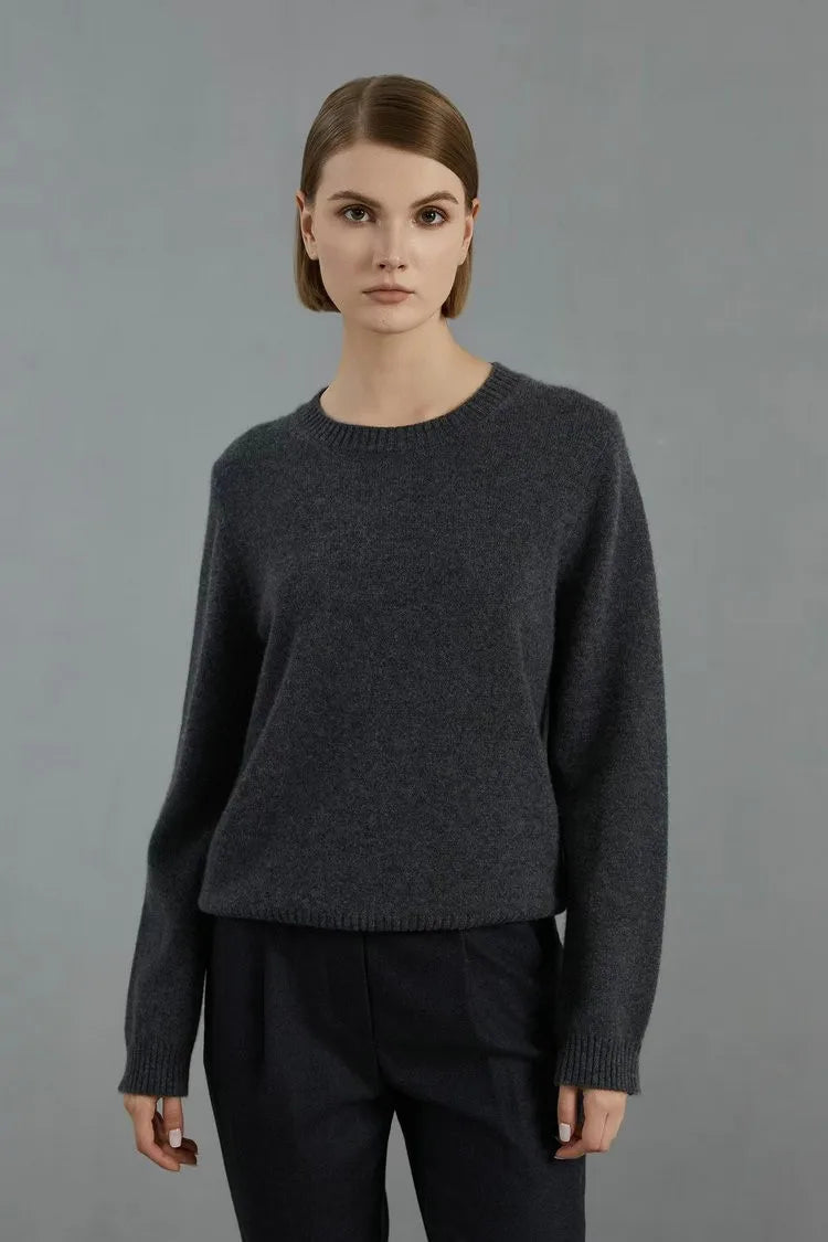 Women’s slim-fit cashmere sweater in Baltic Sea, featuring ribbed cuffs with metal accents. Model standing with arms straight — From Borcelleclothes.