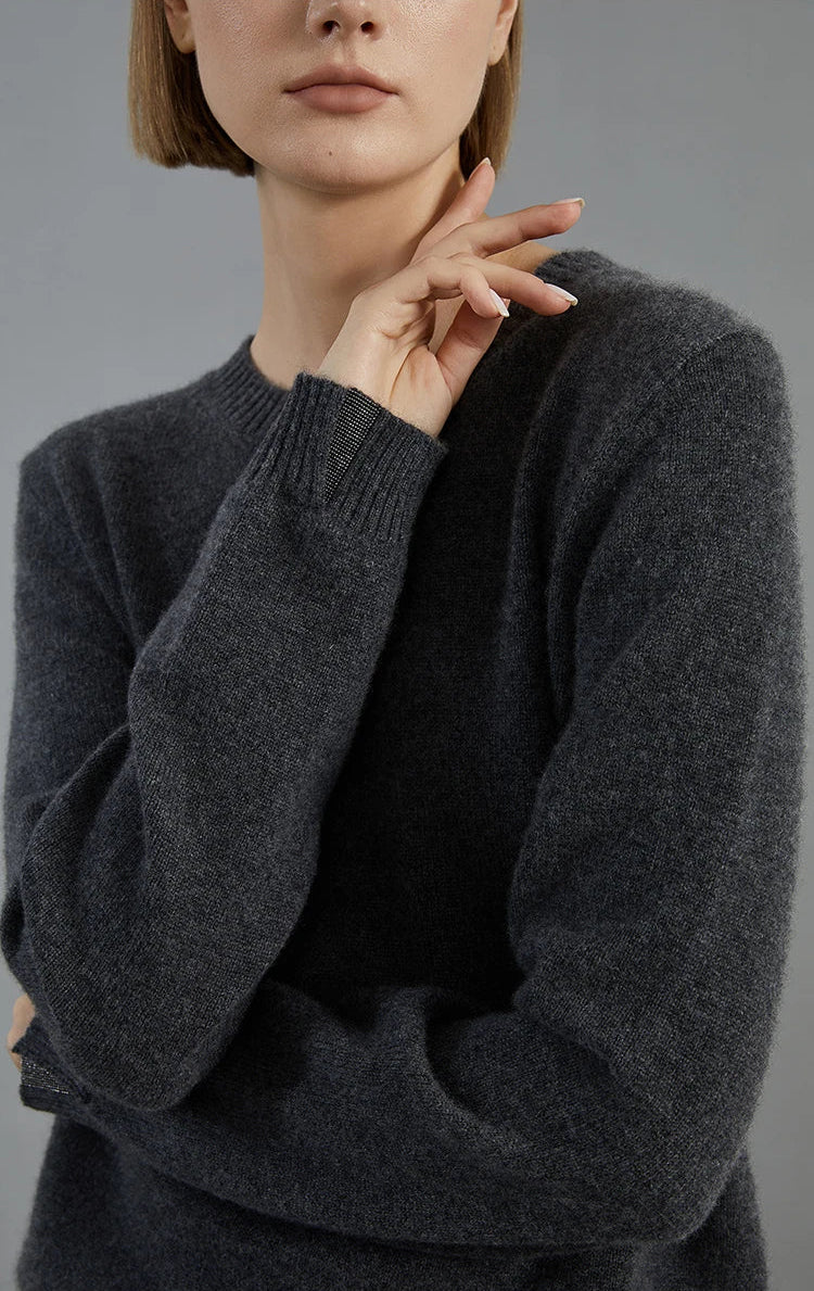 Raised arm gesture reveals the slit cuff and bead insert in the Baltic Sea cashmere sweater — From Borcelleclothes.