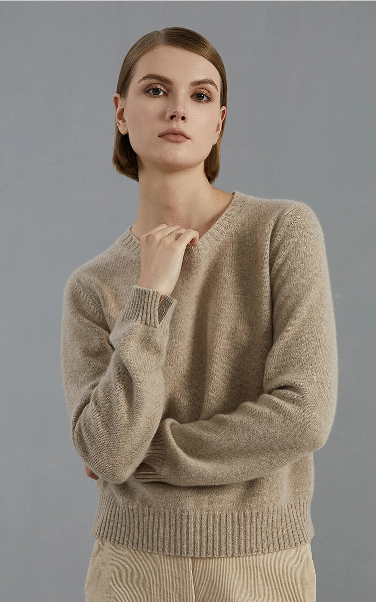 Model in Sandrift sweater touching the neckline, revealing the natural sheen of cashmere — From Borcelleclothes.