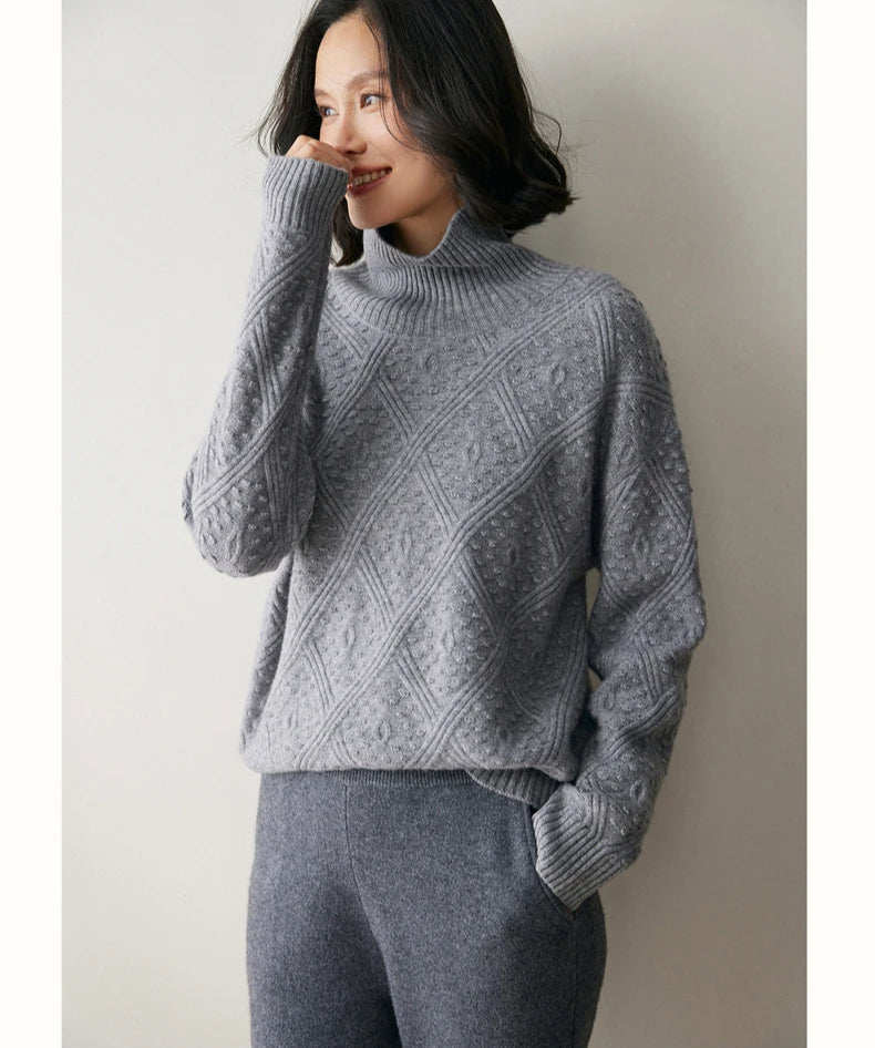 Model in French Grey cashmere sweater touching her nose, showing soft neckline and raised lattice pattern — From Borcelleclothes.