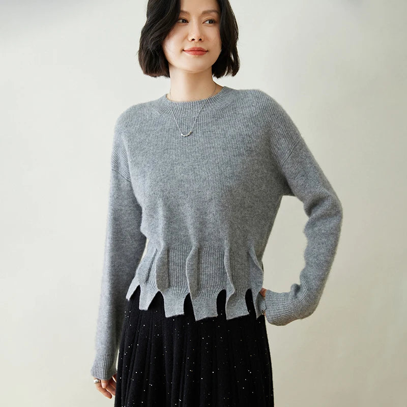 Model touching the sculpted bottom section of Oslo Grey cashmere sweater – From Borcelleclothes.