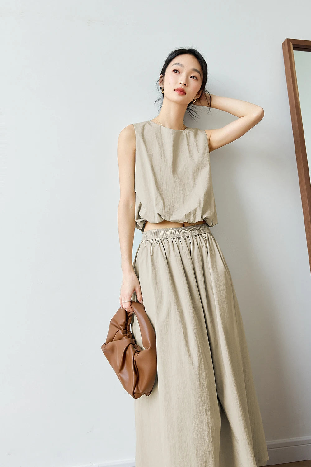 Close gesture of model adjusting hair — Coral Reef top shown with subtle texture and quiet volume. From Borcelleclothes.