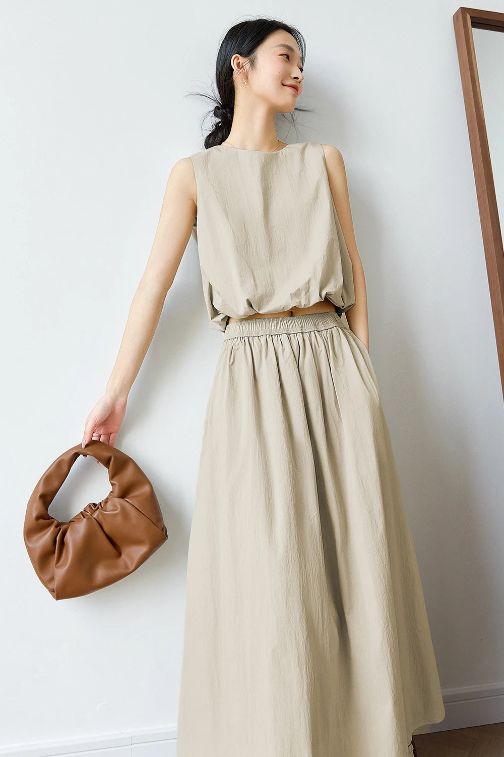 Woman in Coral Reef two-piece set holding a brown bag — sleeveless top and flowing skirt styled with natural ease. From Borcelleclothes.