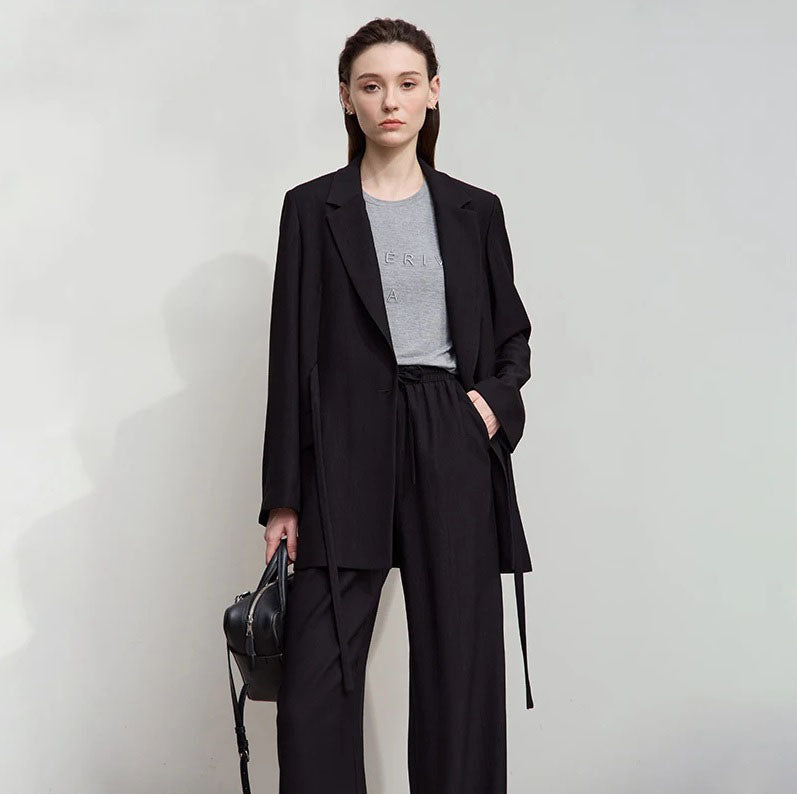 Women’s crinkled viscose blazer in Onyx, with deep textured folds, notch lapels, flap pockets, sculptural triangular button, and belt threaded through side openings. From Borcelleclothes.