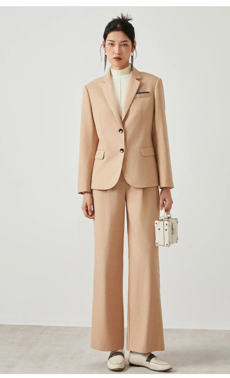 Woman in Desert Sand blazer holding a white bag, styled with accessories. From Borcelleclothes.