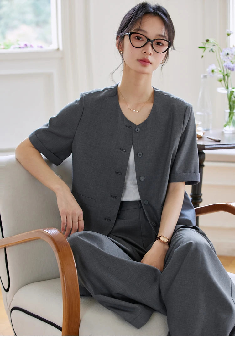 Model sitting in a relaxed pose with one leg inside the chair wearing the Fiord set. From Borcelleclothes.