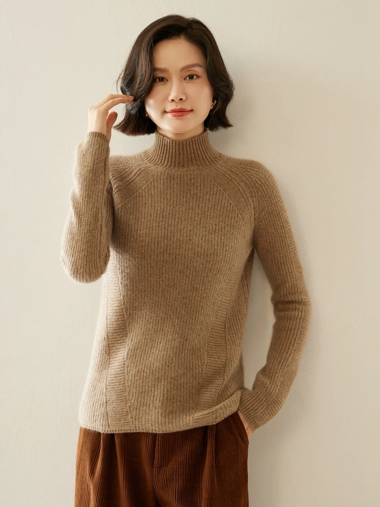 Model in Coffee With Cream Fisherman rib sweater, adjusting hair; diagonal chest lines and high neckline visible — From Borcelleclothes.