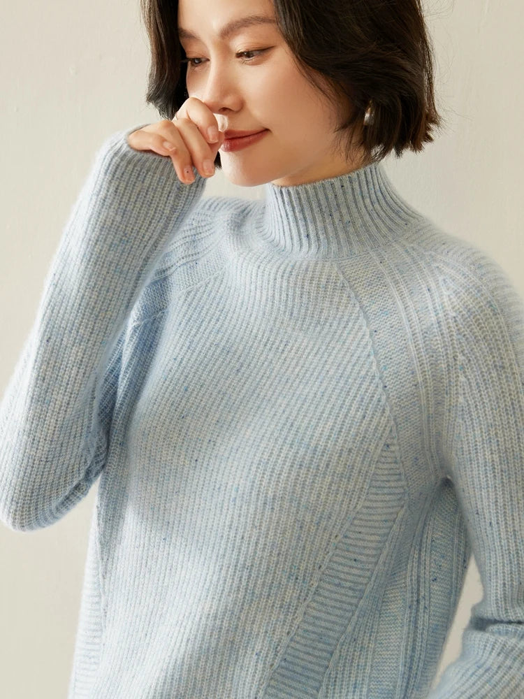 Model in Winter’s Breath sweater touching her nose, with soft neckline and purl texture catching light — From Borcelleclothes.