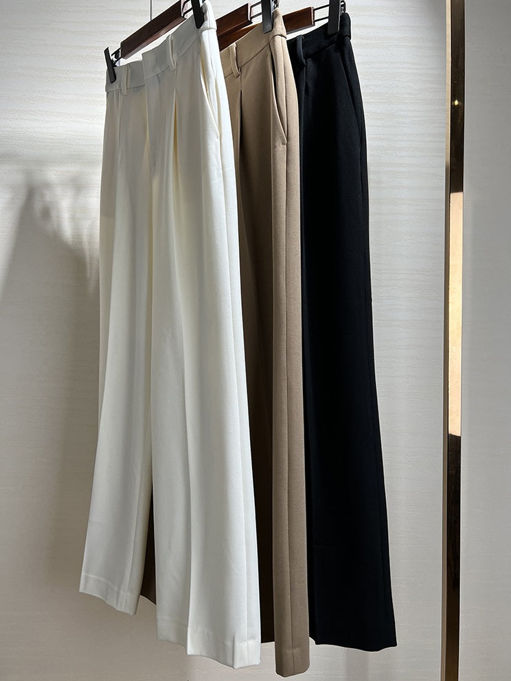 Collection of wool-blend trousers in Platinum, Almond Frost, and Onyx displayed on hangers. From Borcelleclothes.