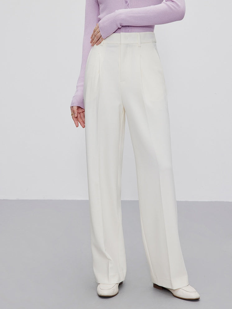 Woman touches the waistband of Platinum wool-blend trousers, highlighting the clean construction. From Borcelleclothes.