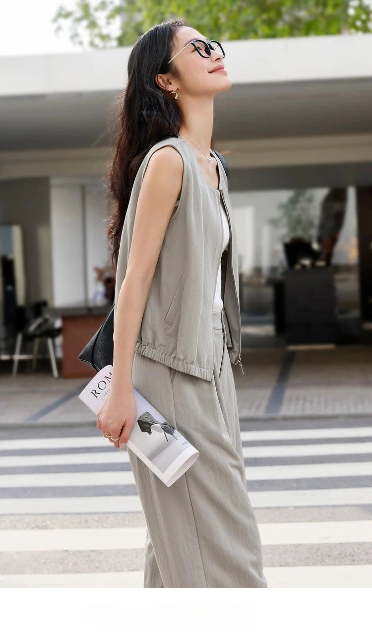 Woman in French Grey two-piece set standing in profile, showcasing the sleeveless jacket and trousers. From Borcelleclothes.