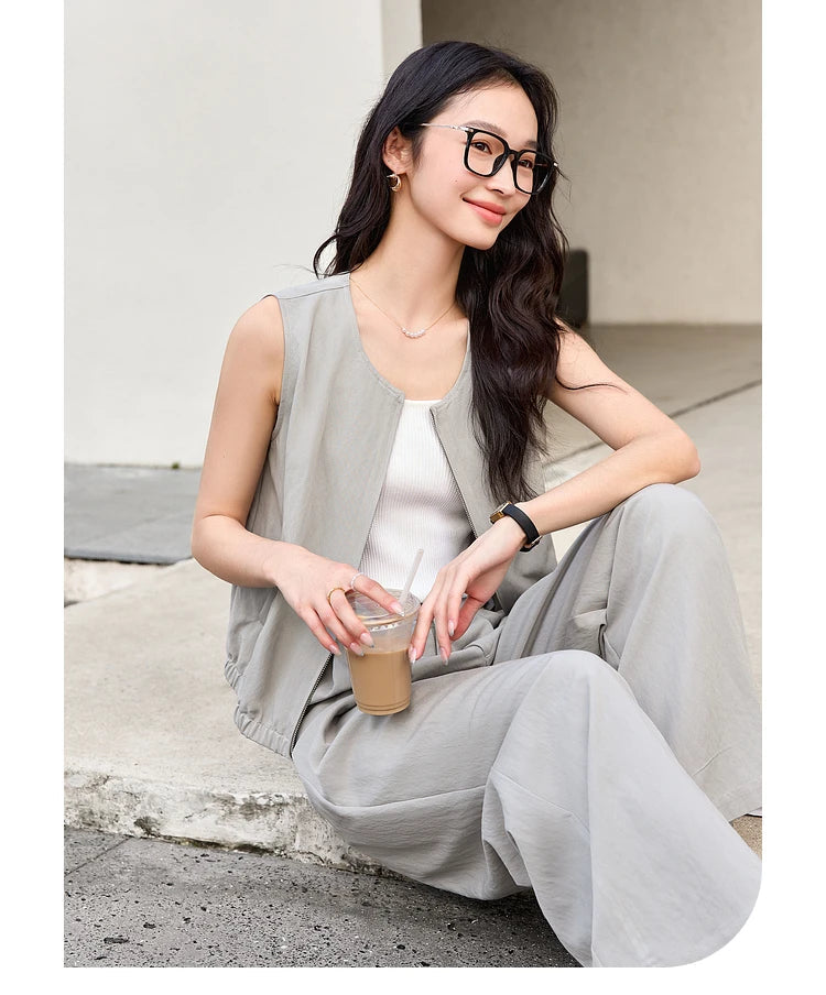Model seated on concrete with a cup of coffee, wearing the French Grey outfit. From Borcelleclothes.