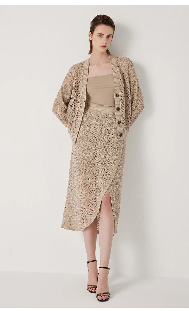 Model in Vanilla linen lace cardigan leaning softly against a wall, the openwork catching ambient light. From Borcelleclothes.