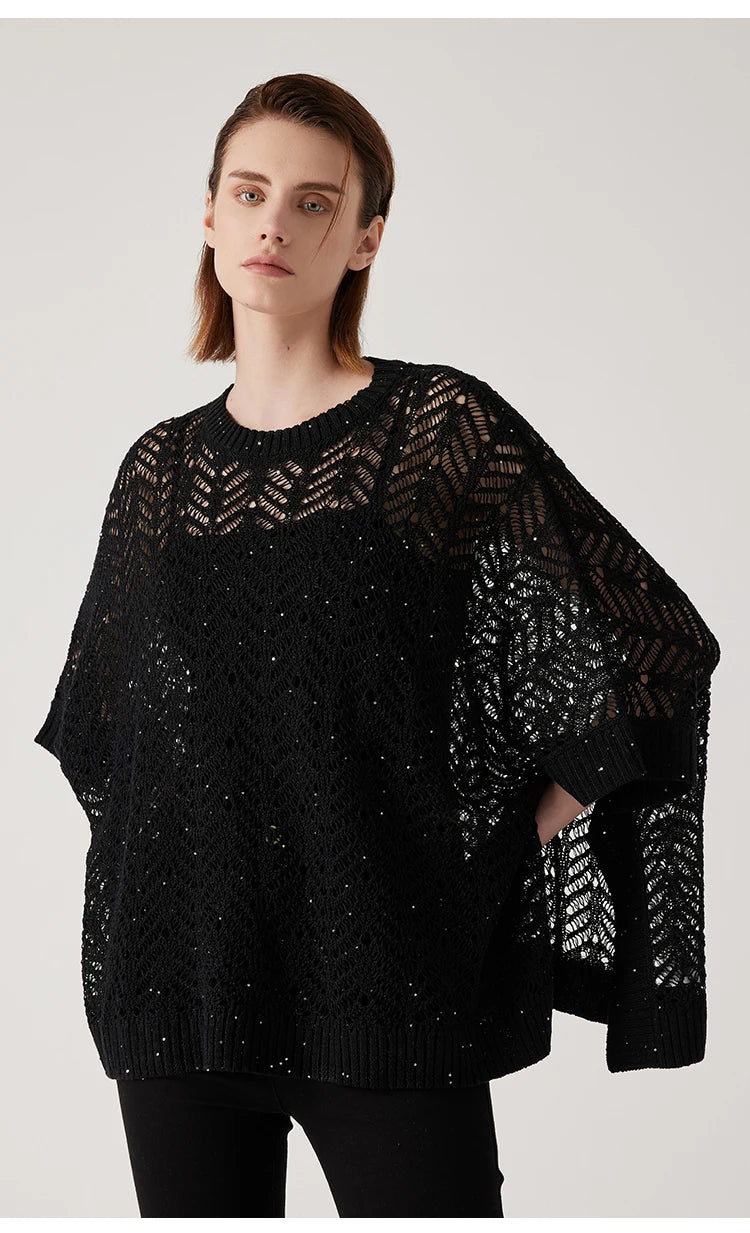 Woman wearing black linen lace poncho, hands on hips, showing sculptural drape and silver sequin detailing. From Borcelleclothes.