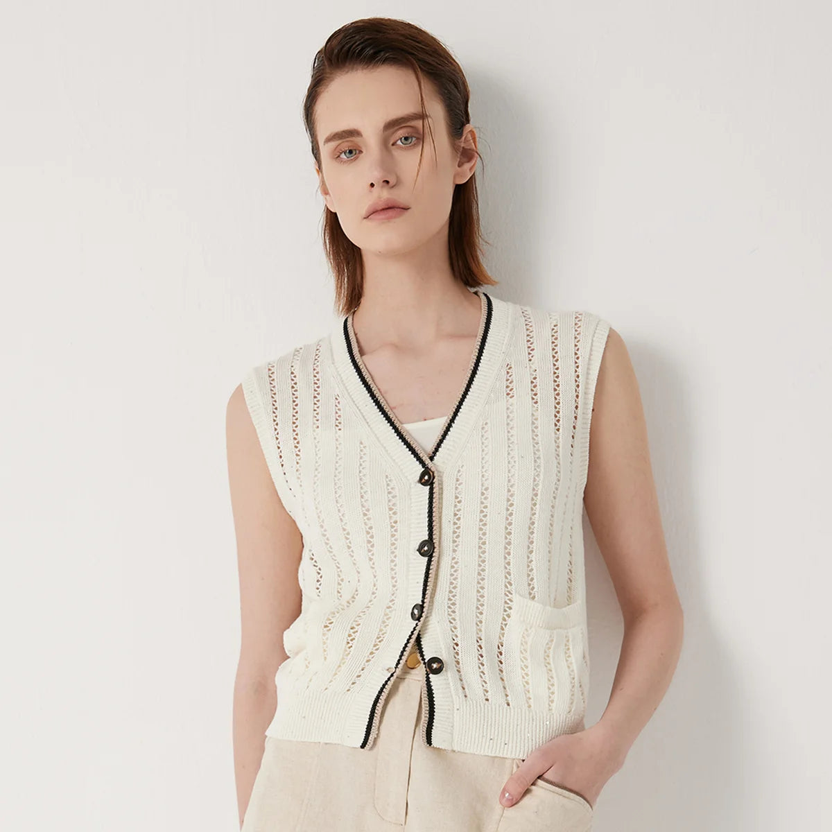 Women's linen lace vest in Pearl Bush with vertical stockinette and lace stripes, contrast ribbed trim, and a single patch pocket—minimal, structured, and quietly striking. From Borcelleclothes.
