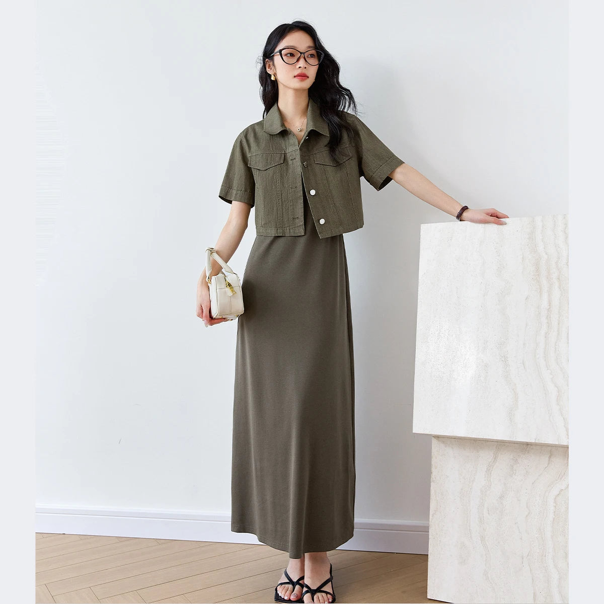 Woman in Makara set resting hand on a minimalist white structure, blending poise and ease. From Borcelleclothes.