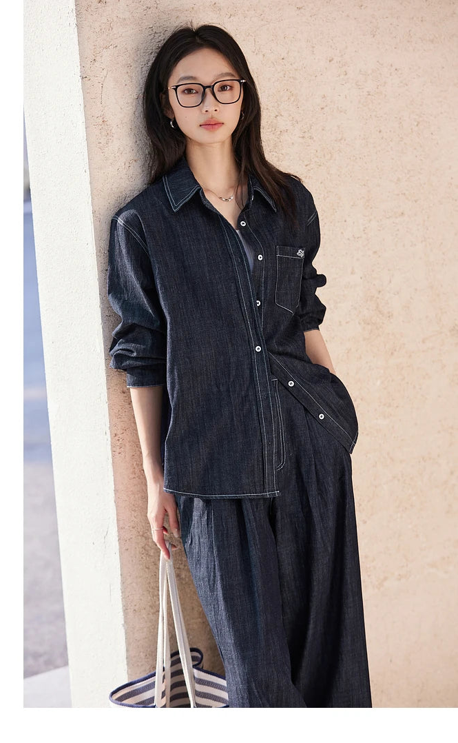 Woman leaning against a wall in Midnight Express set — shirt with SPROUT embroidery and softly structured trousers. From Borcelleclothes.