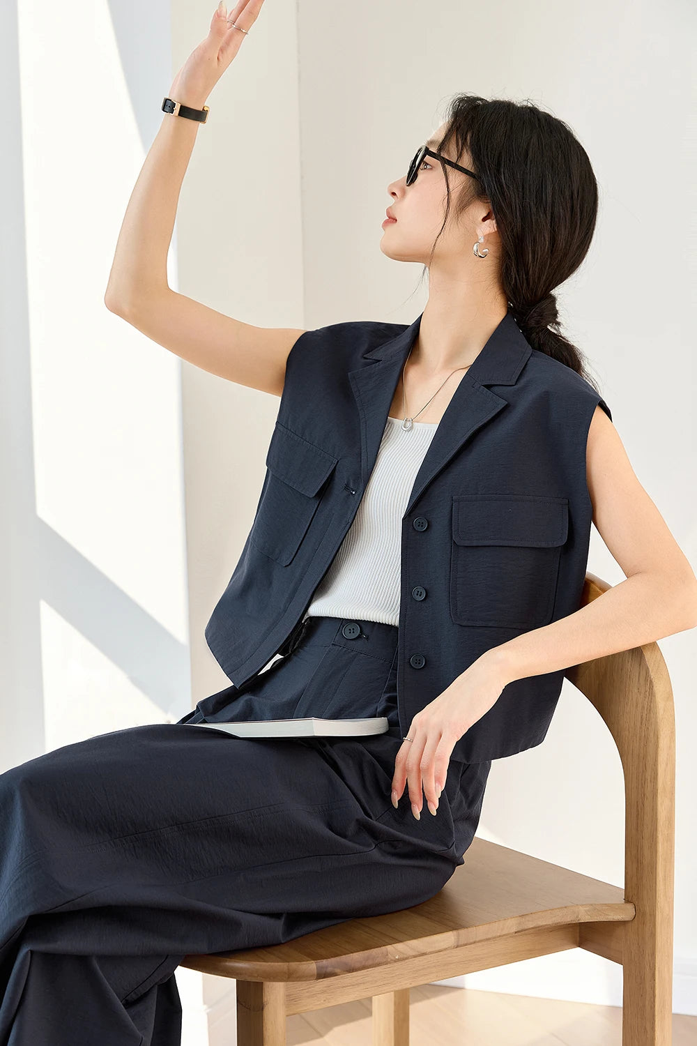 Seated model in Mirage set with one arm lifted — vest and trousers revealing balance between structure and movement. From Borcelleclothes.