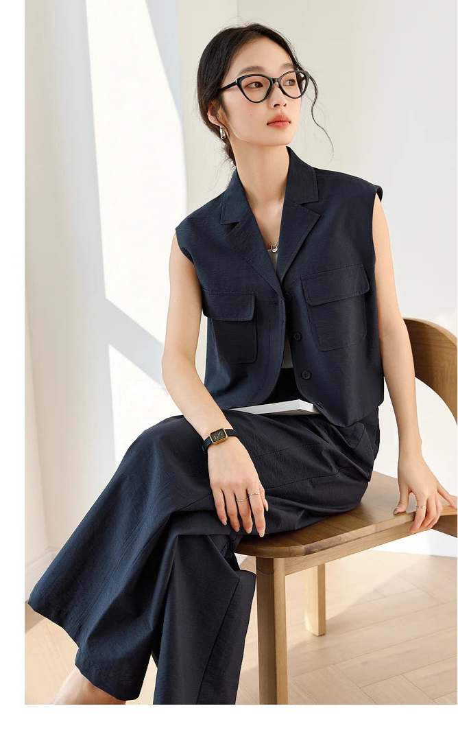 Woman seated in Mirage-colored two-piece suit, relaxed yet poised in a structured sleeveless vest and straight-leg trousers. From Borcelleclothes.