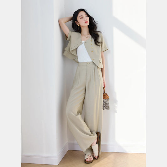 Women’s two-piece set in Moon Mist color featuring a short-sleeved jacket with gold buttons and curved details, paired with straight pleated trousers. From Borcelleclothes.