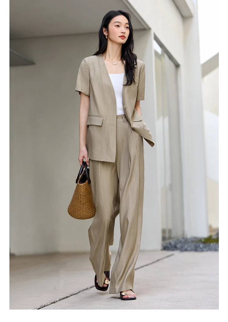 Model holding a woven bag while standing in the Olive Haze two-piece set, emphasizing natural textures. From Borcelleclothes.