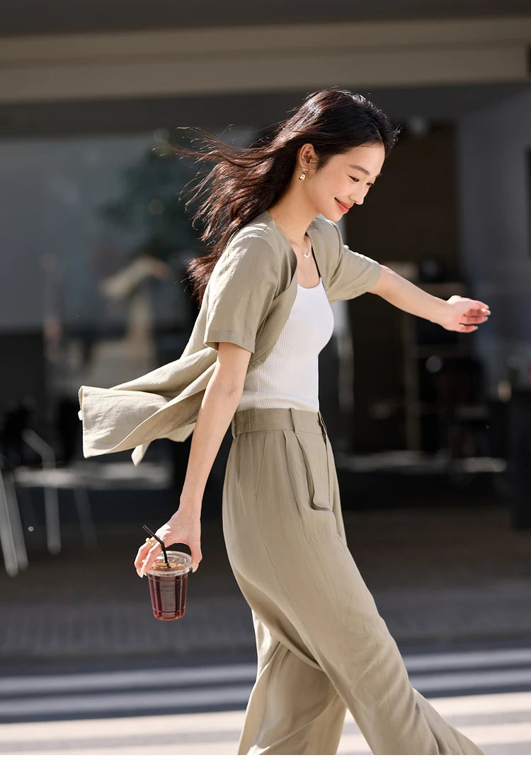 Side view of the model with wind lifting the crinkled fabric of the Olive Haze set, suggesting motion and ease. From Borcelleclothes.