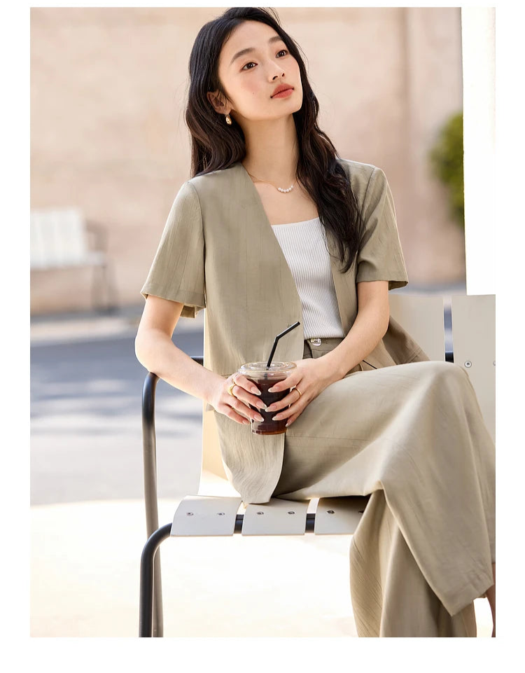 Model seated in a chair with a coffee cup, dressed in the Olive Haze two-piece set with a calm expression. From Borcelleclothes.
