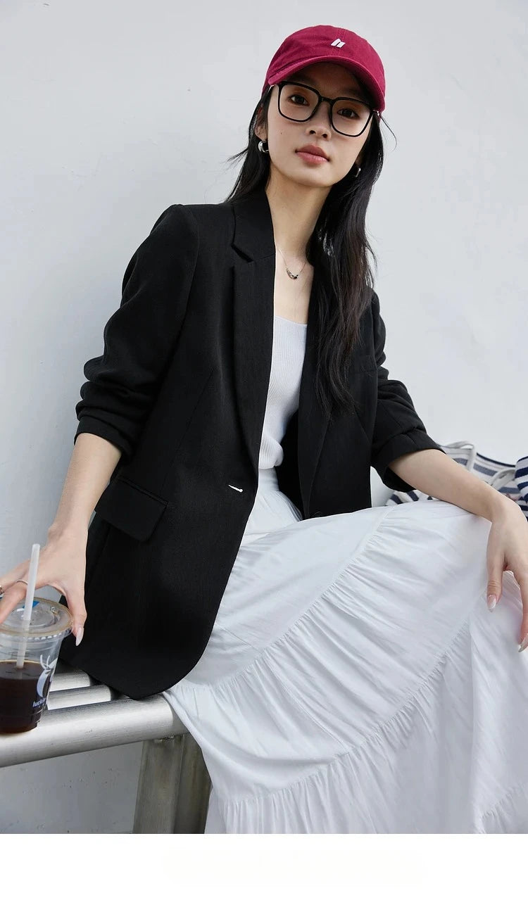 Woman in Onyx Urban Blazer sitting and holding a cup of coffee. From Borcelleclothes.