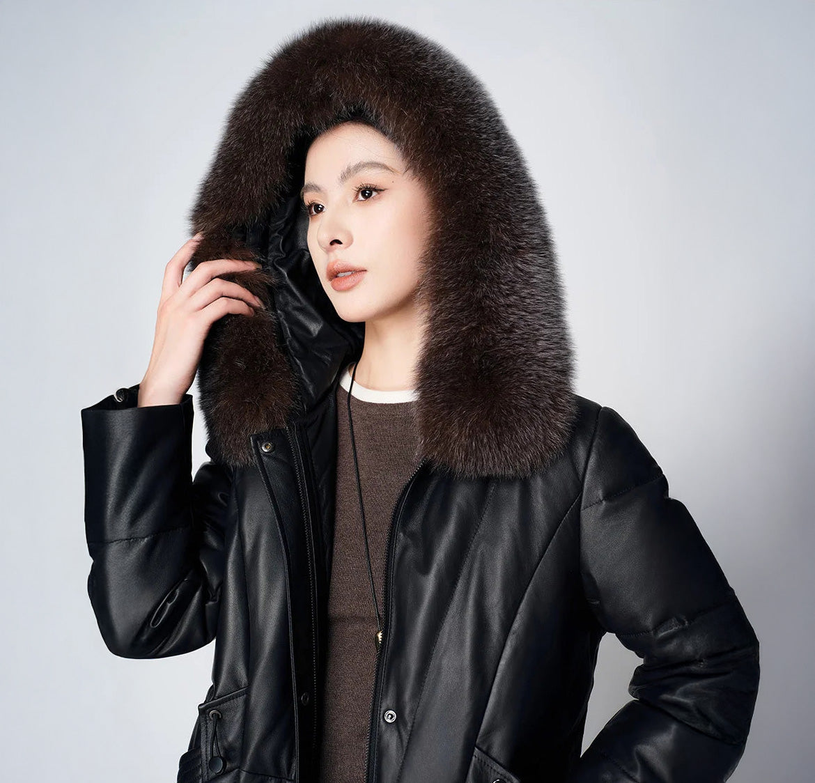 Women's Sheepskin Coat with Hidden Casing in Onyx — model adjusting lifted hood. From Borcelleclothes.