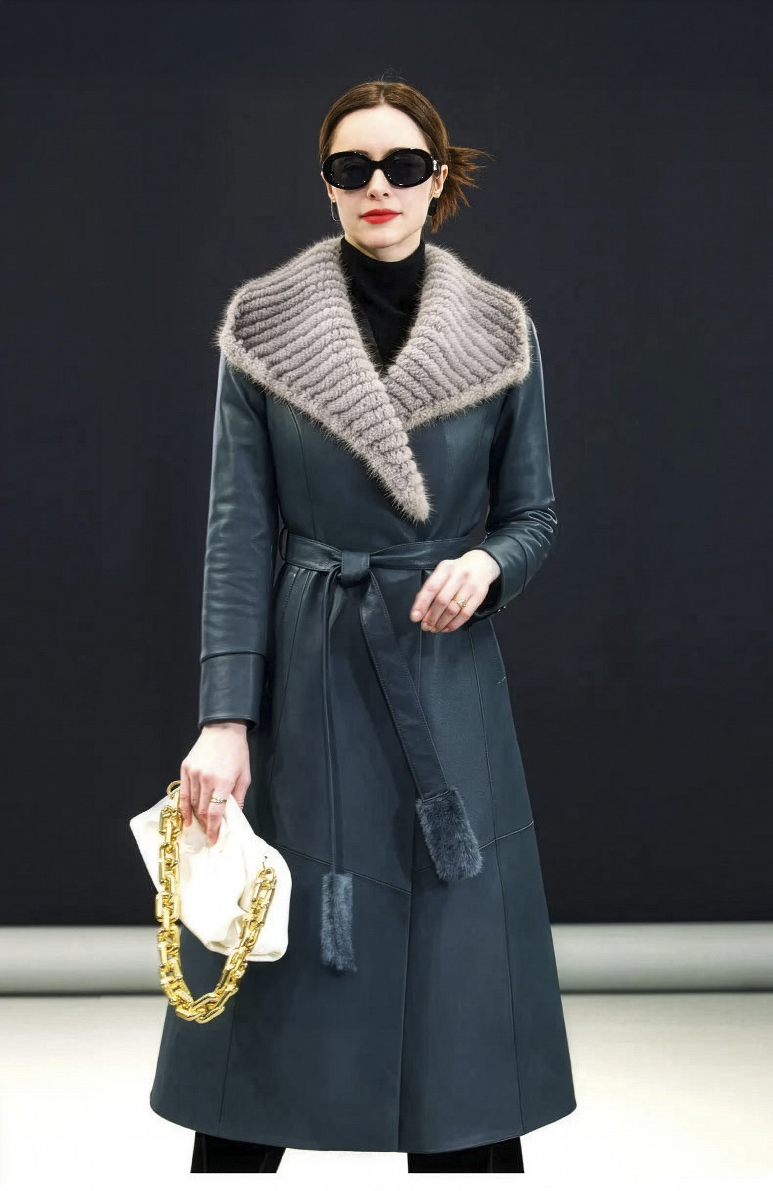 Model in Independence coat holding a white bag, fur collar spread across shoulders — From Borcelleclothes.