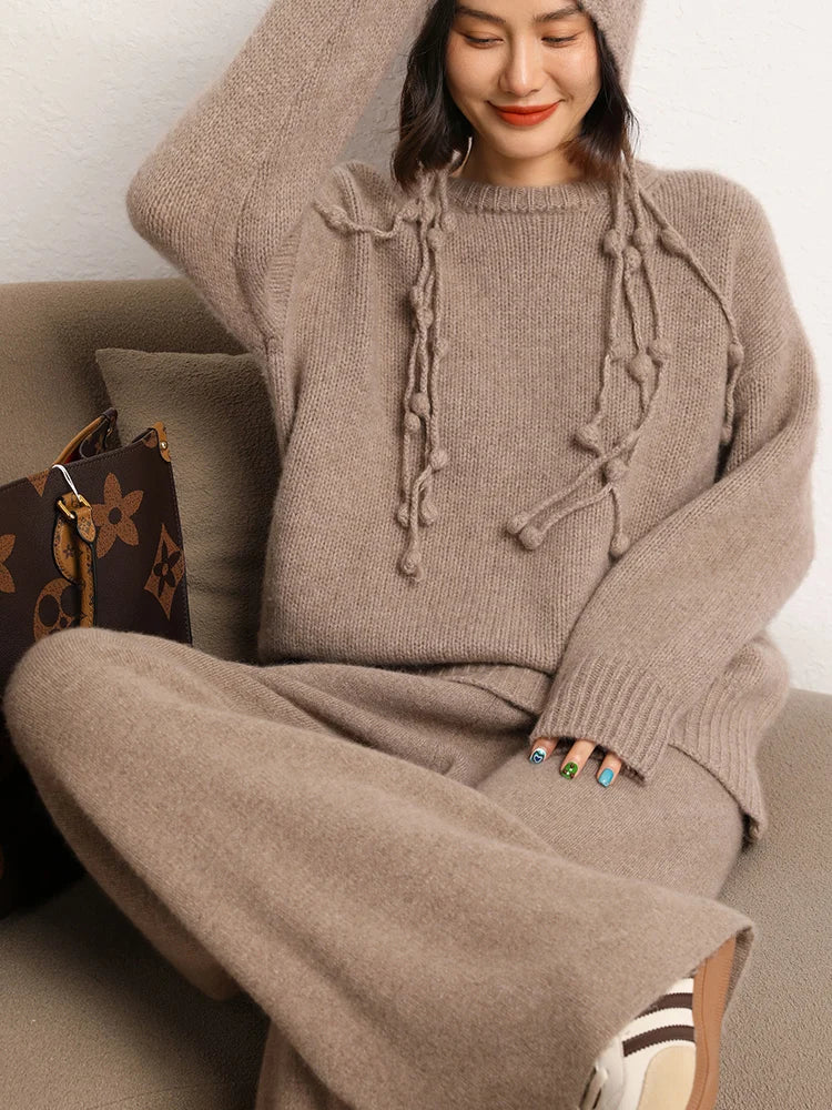 Model with crossed legs on sofa in Sandrift straight-cut cashmere trousers — From Borcelleclothes.