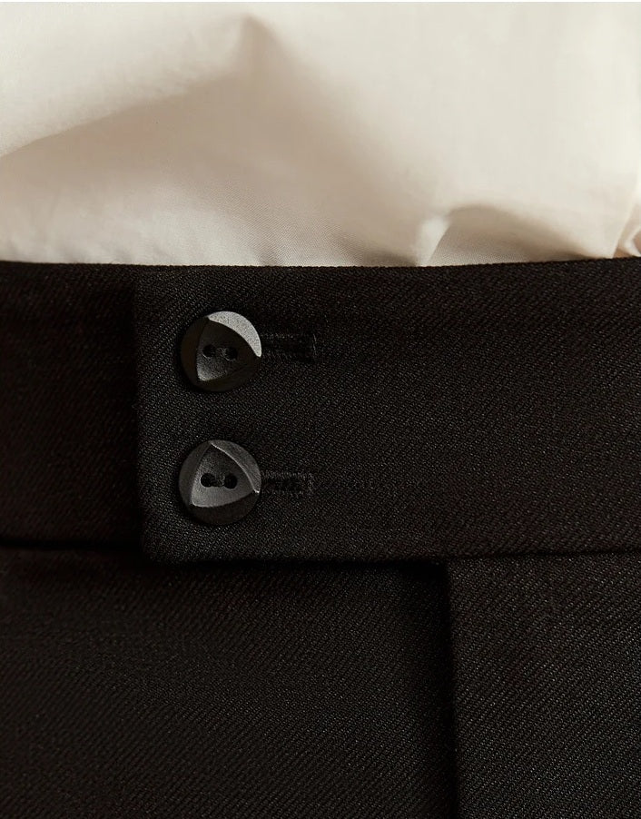 Close-up of tonal decorative buttons at the waistband of Onyx trousers, part of the garment’s minimal expression. From Borcelleclothes.