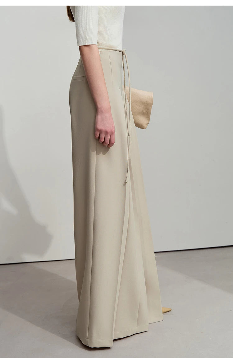 Side view of model wearing draped trousers in Silk color, showing fabric volume and silhouette. From Borcelleclothes.