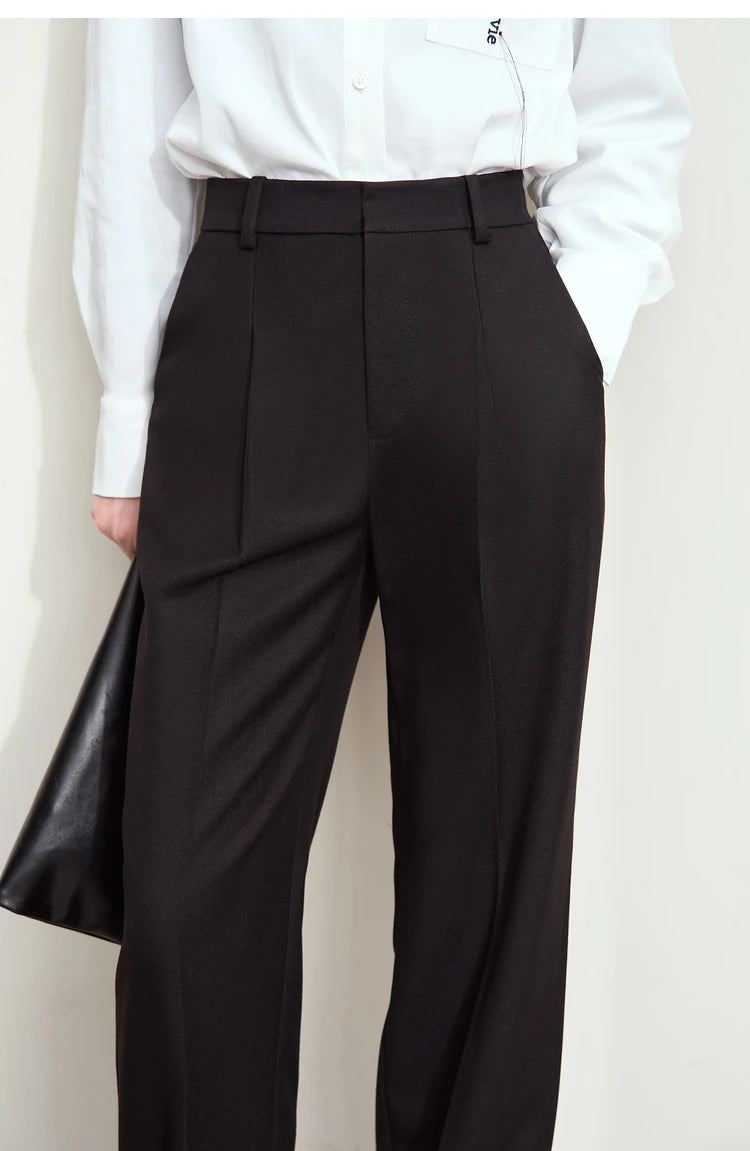 Model in Onyx tailored trousers, upper front view — flat waistband and symmetrical pleats create a composed silhouette. From Borcelleclothes.