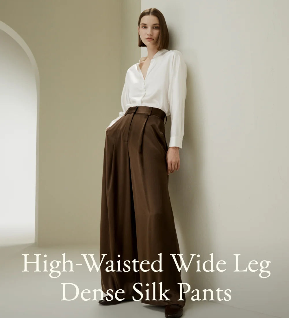 Model in Cafe Noir silk trousers leaning shoulder against the wall, merging structure with softness. From Borcelleclothes.