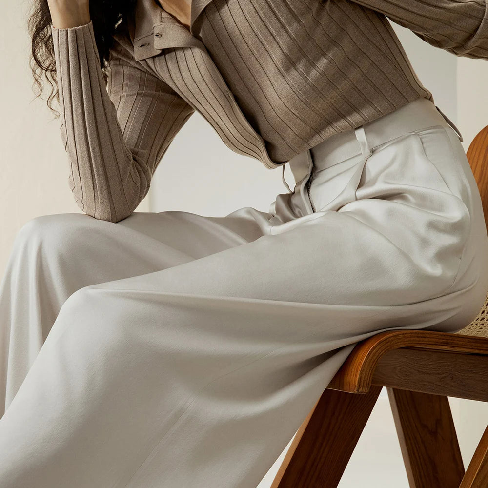 Model in Platinum silk trousers sitting with elbow on knee, evoking composed elegance and natural ease. From Borcelleclothes.