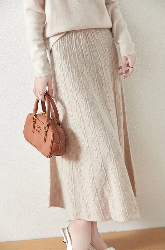Textured merino wool skirt in Pale Silver, model holding bag, showing full silhouette with soft vertical and wave knit — From Borcelleclothes.