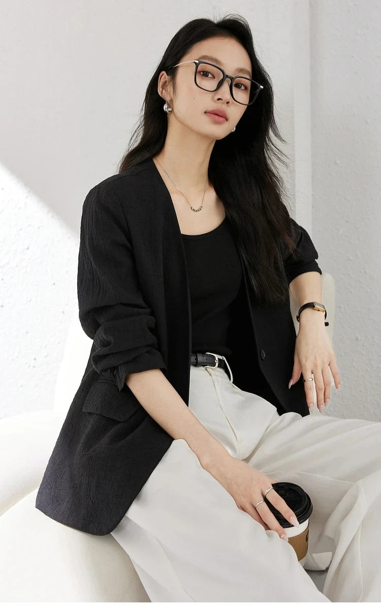 Woman holding a coffee cup while wearing an Onyx textured pinstripe crinkle blazer. From Borcelleclothes.