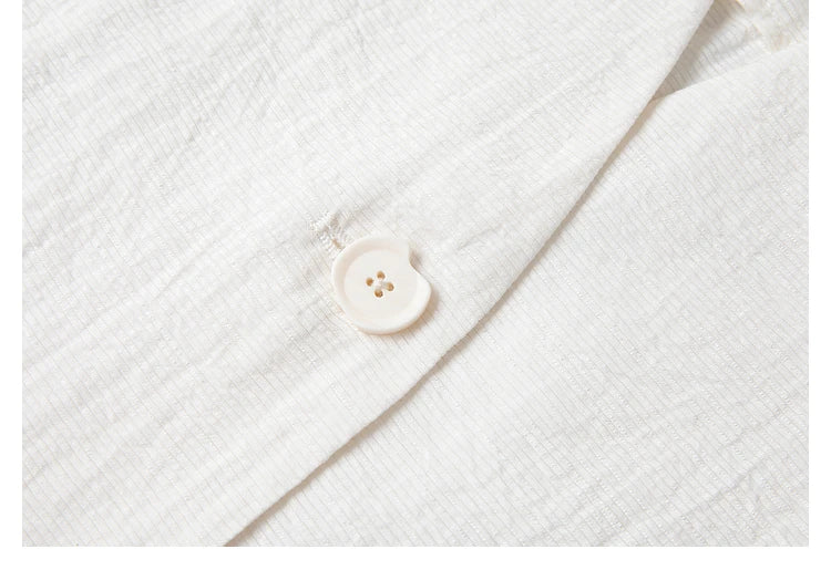 Close-up of tonal button on a Pearl Bush textured pinstripe crinkle blazer. From Borcelleclothes.
