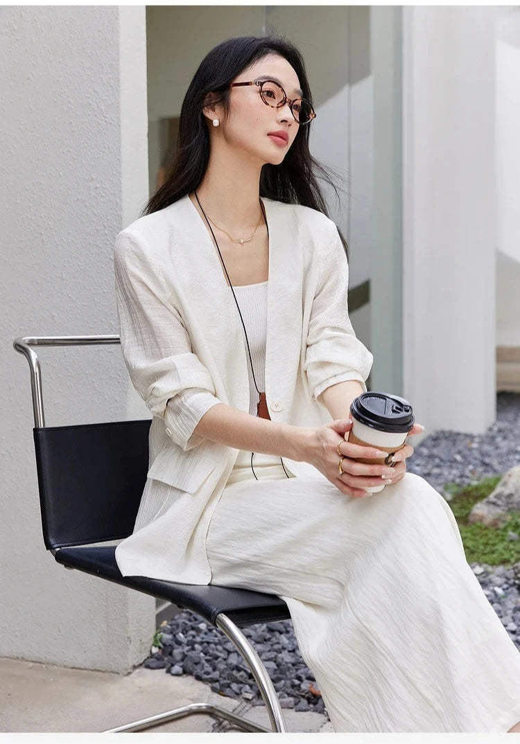 Model sitting on a chair in a Pearl Bush textured pinstripe crinkle blazer. From Borcelleclothes.