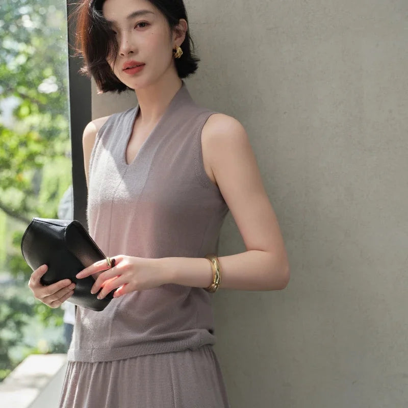 Model wearing the Morning Mist V-neck cashmere top while holding a small bag — From Borcelleclothes.