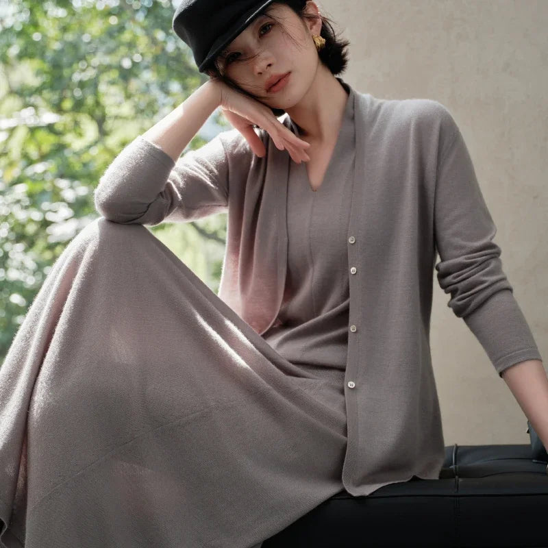 Model sitting and gently touching her face in the Morning Mist V-neck cashmere top — From Borcelleclothes.