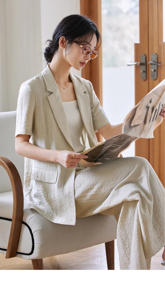 Woman in Wild Sand outfit sitting and reading a newspaper in a serene setting. From Borcelleclothes.