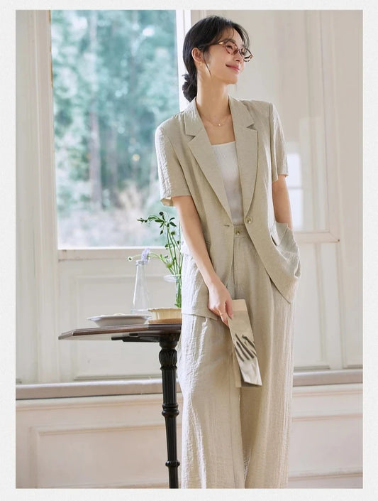 Women's two-piece set in Wild Sand, featuring a short-sleeved blazer with notch lapels and crinkled wide-leg trousers, shown in natural light. From Borcelleclothes.