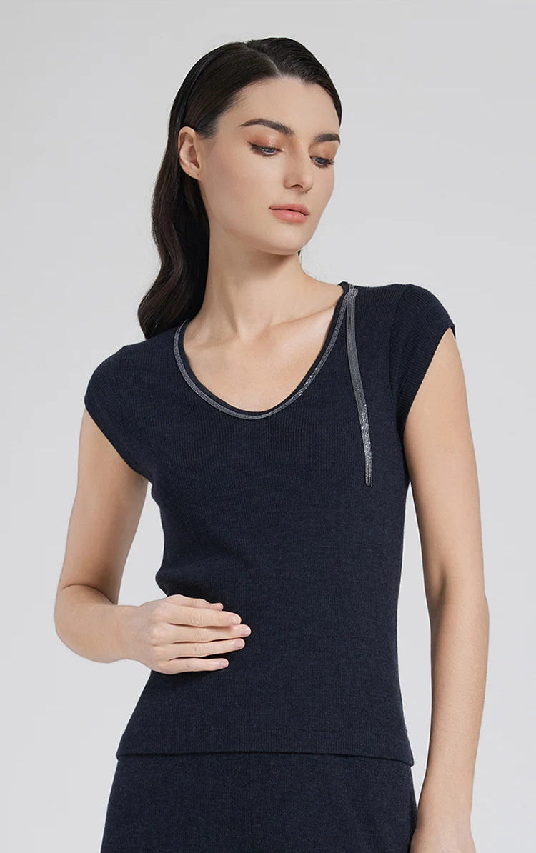 Model wearing women's wool-silk top in Black Pearl with rhinestone trim, gently touching her stomach. From Borcelleclothes.