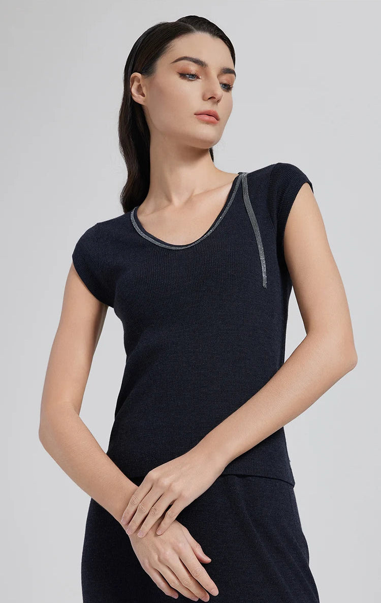 Model in Black Pearl wool-silk top with rhinestone detail, touching her wrist in a poised stance. From Borcelleclothes.