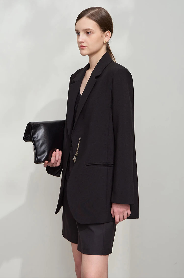 Woman turned slightly side in Onyx wrap blazer with golden pendant – From Borcelleclothes.