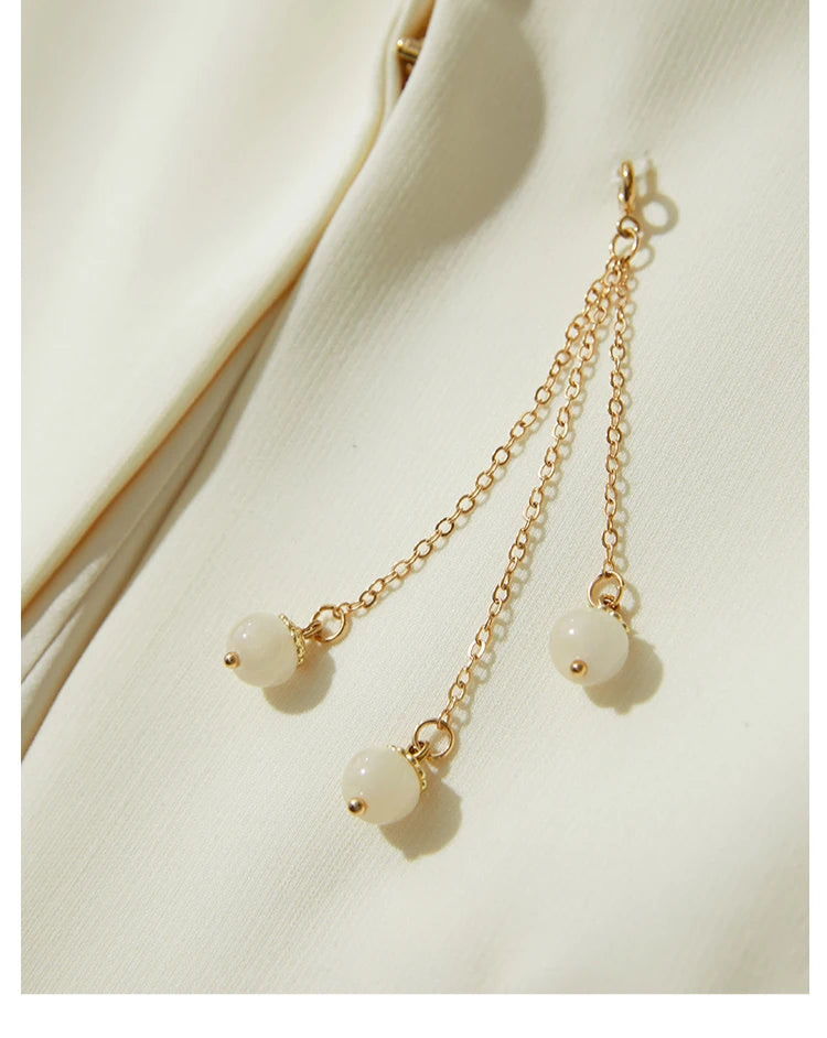 Close-up of golden pendant detail on Pearl Bush wrap blazer – From Borcelleclothes.
