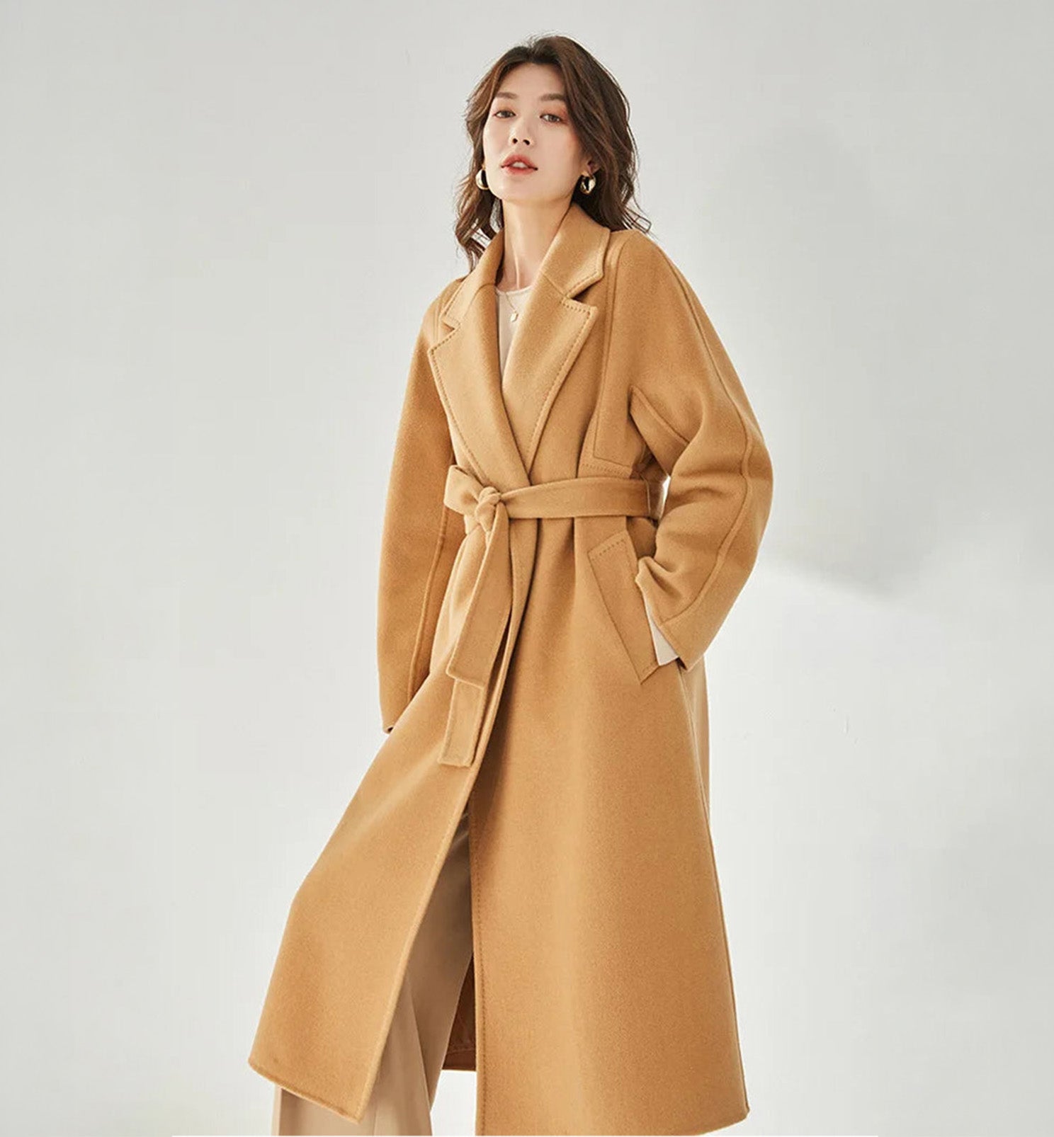 Women's Wrap Coat Redefined in Brown Sugar—crafted from a luxurious blend of Merino wool and cashmere. Featuring square gussets for a structured silhouette, notch lapels, a single-welt pocket design, and an adjustable belt, this mid-calf wrap coat blends modern tailoring with timeless elegance. From Borcelleclothes.